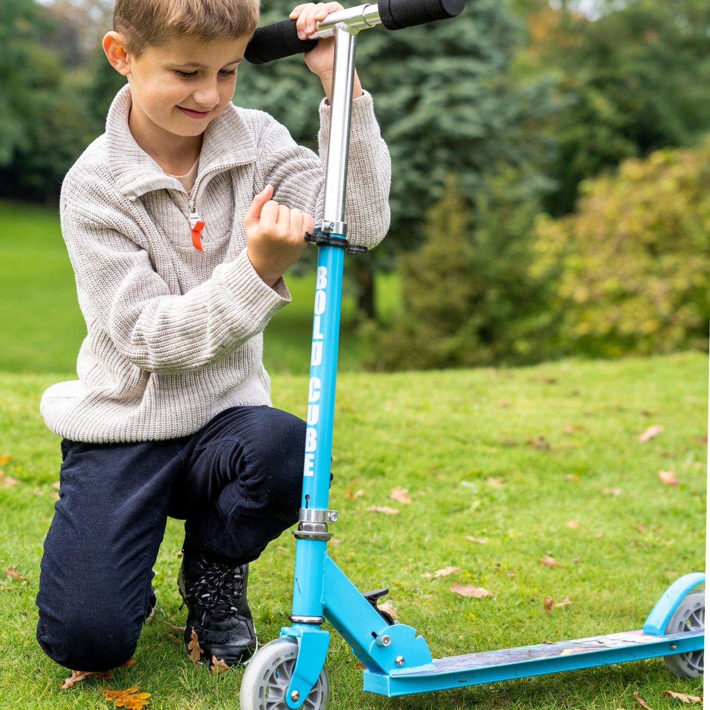 Child playing with a blue scooter on grass