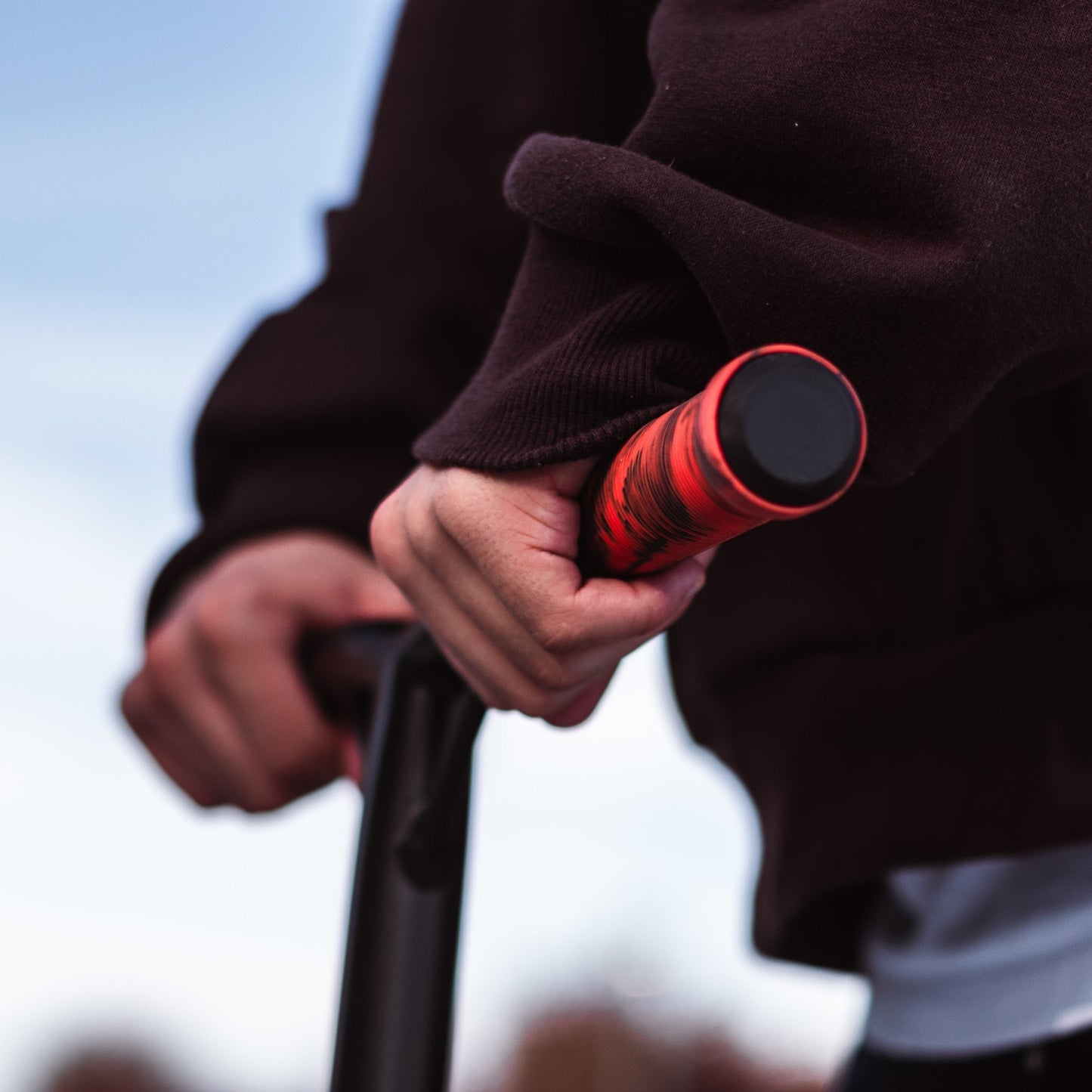 Person holding a red and black cylindrical object against a blurred background