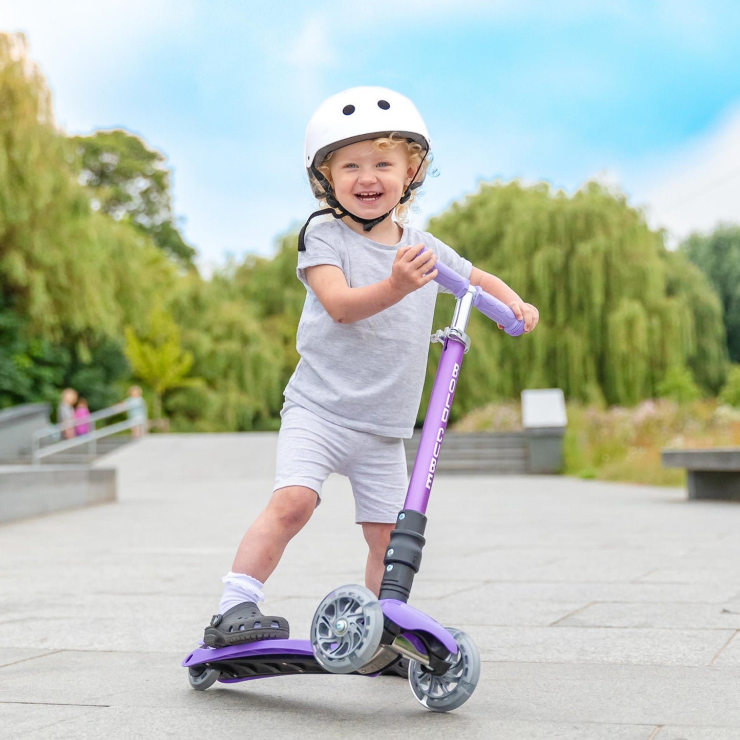 Child riding a purple scooter in a park