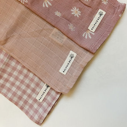Three folded fabric swatches with floral, checkered, and plain patterns on a white background.