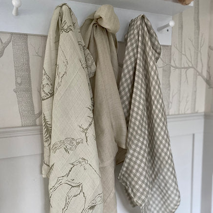 Three fabric items hanging on a rack against a wall with a patterned design.