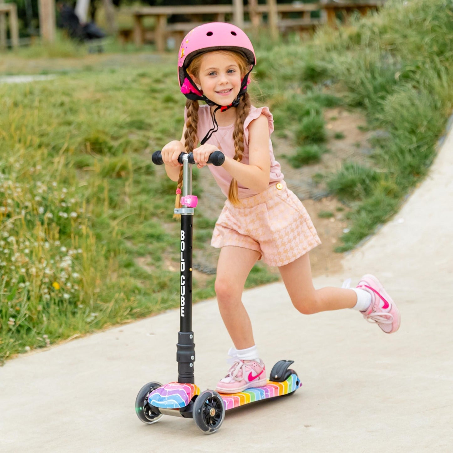 Child riding a scooter with a helmet on a path outdoors