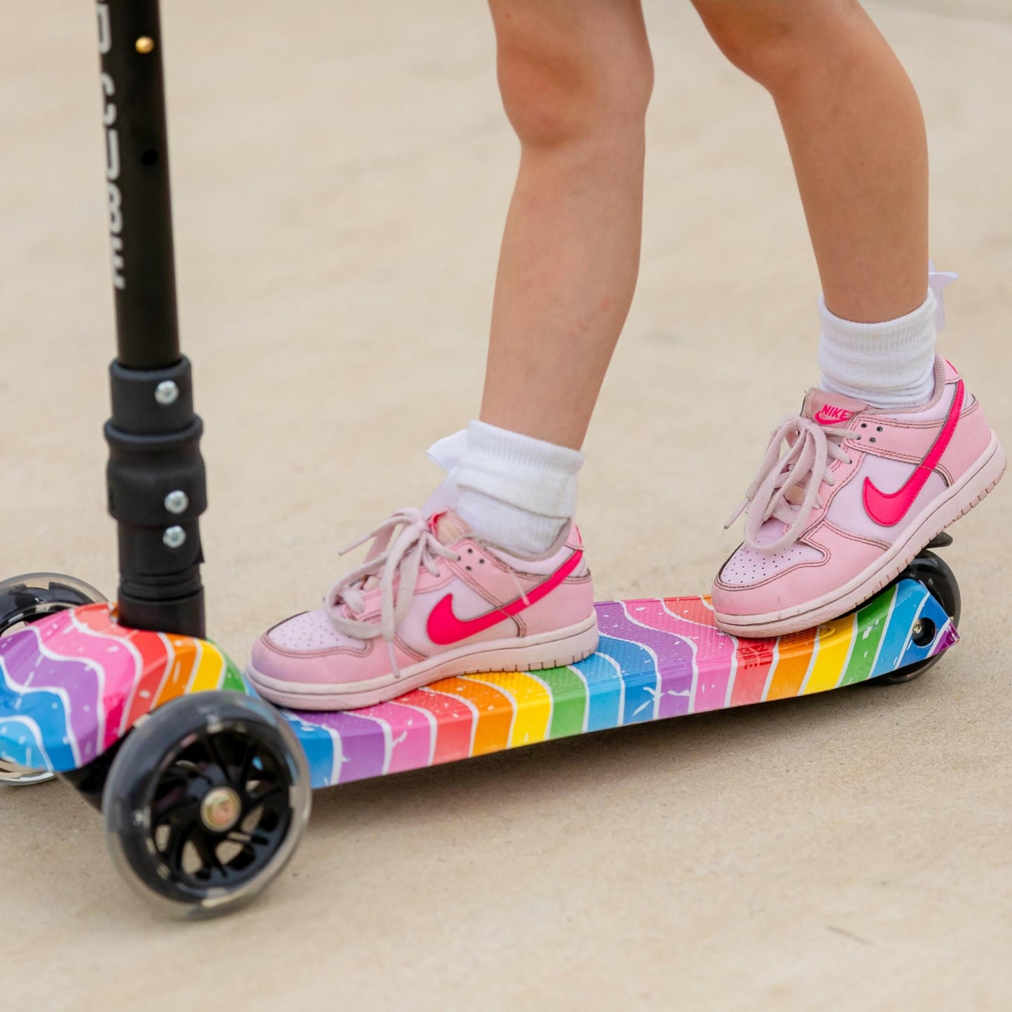 Person riding a colorful scooter with pink shoes on a light background