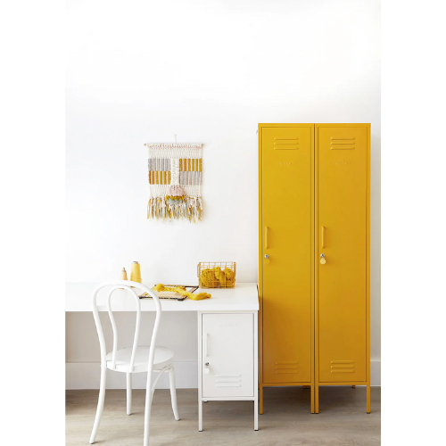 Yellow locker next to a white table with a chair in a room.