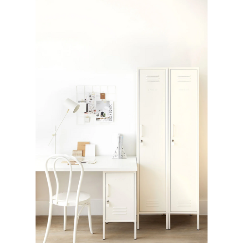 White desk with chair and tall white locker against a light wall.