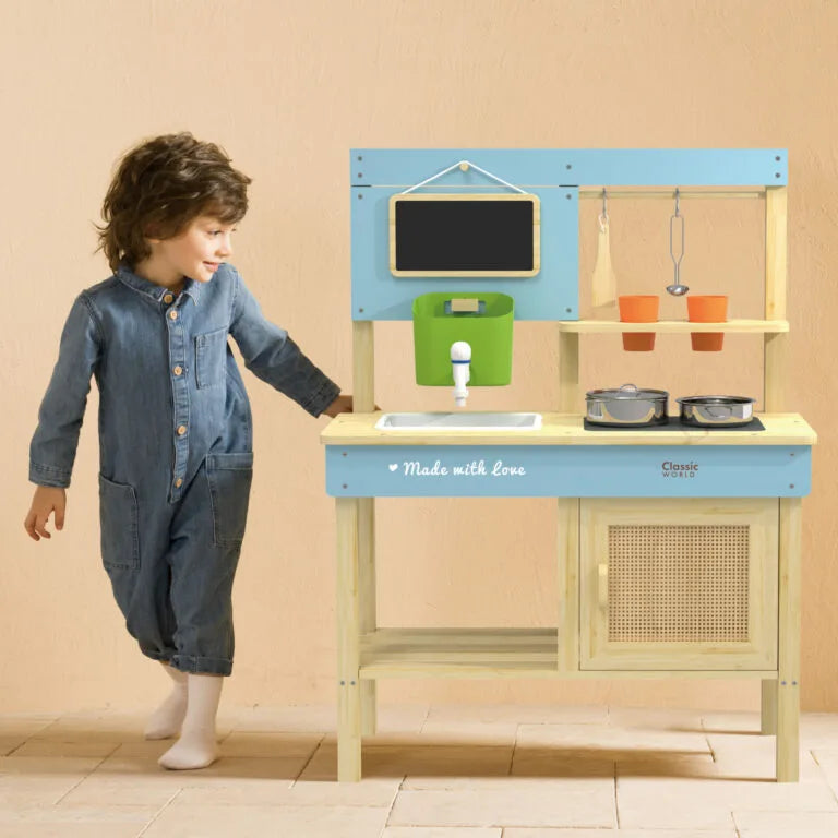 Child playing with a toy kitchen set against a beige wall.