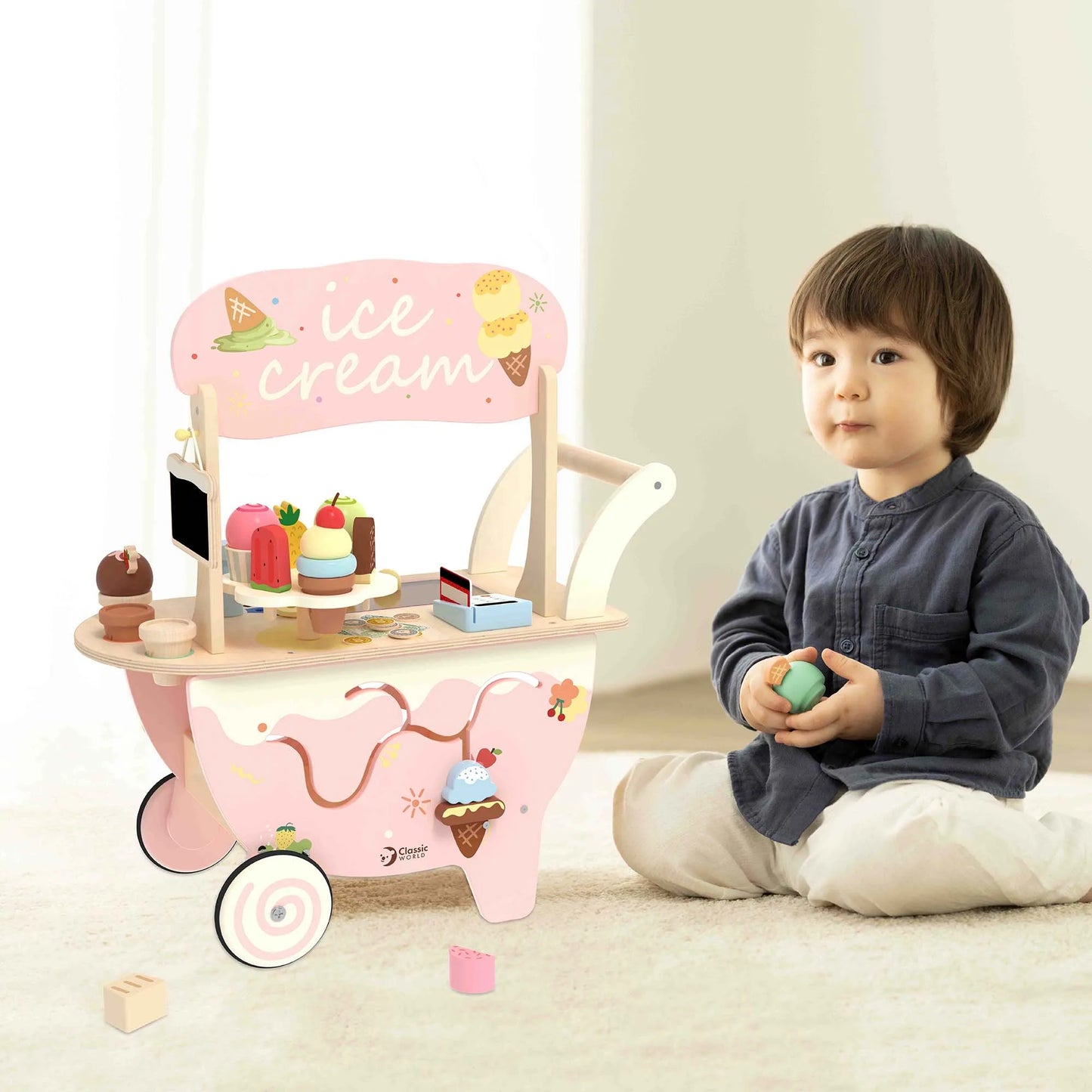 Child playing with a pink toy ice cream cart on a light-colored floor.