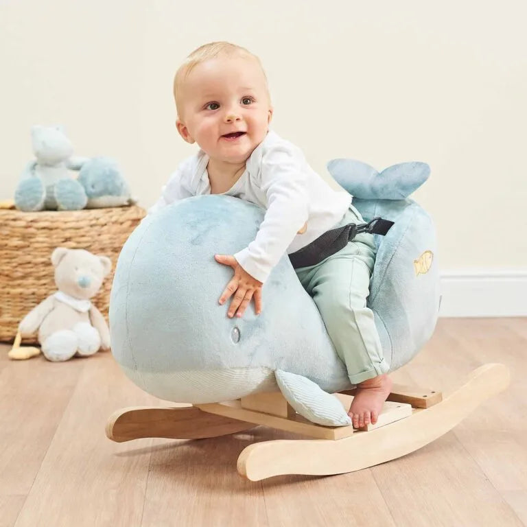 Baby sitting on a blue rocking toy with a neutral background