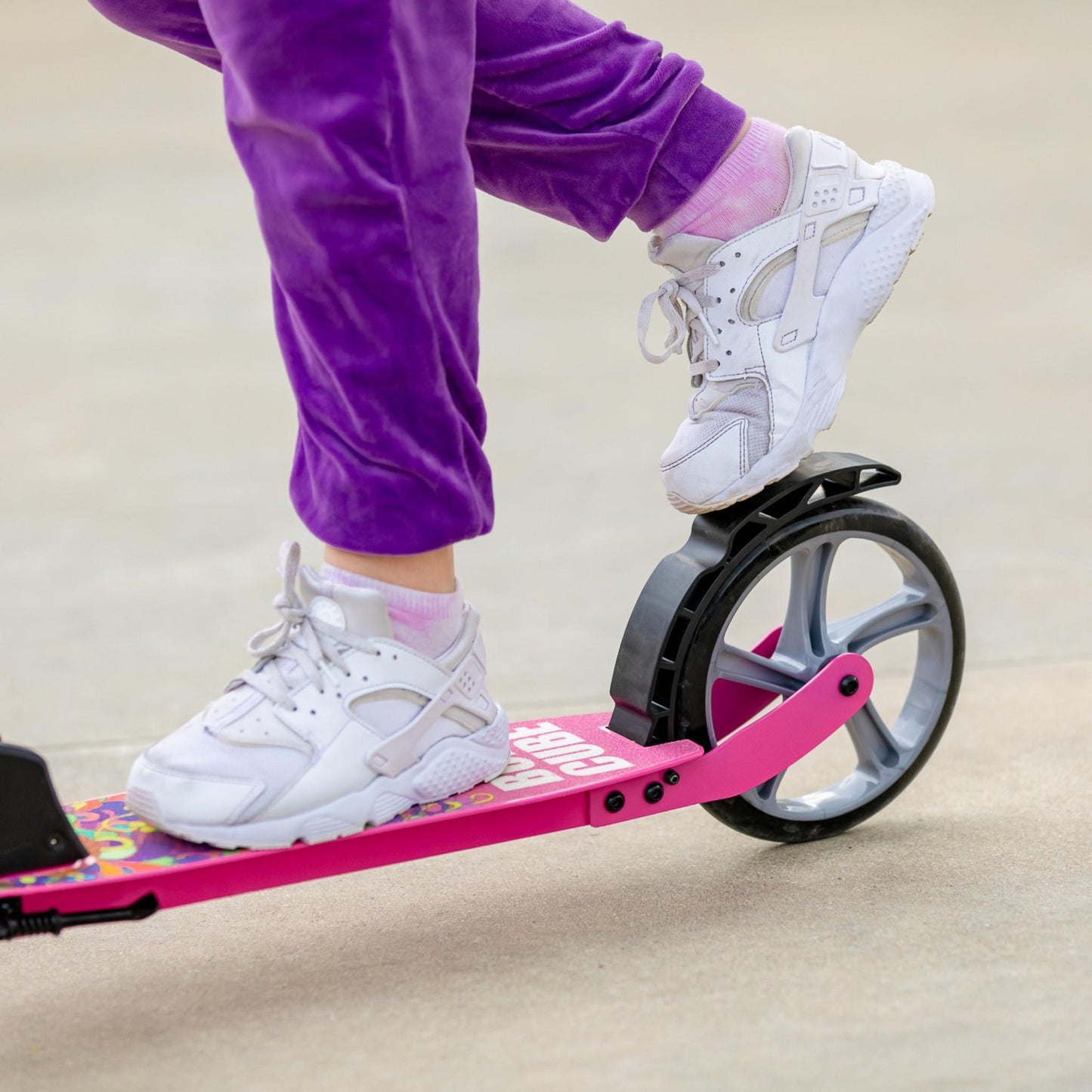 Person riding a pink balance board with one foot on a light background
