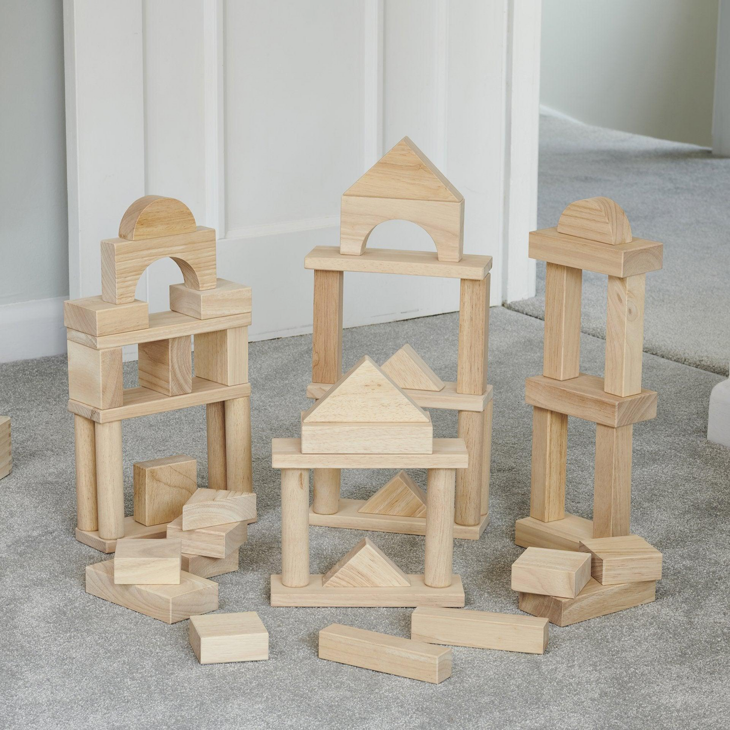 Set of wooden building blocks on a gray floor with a white wall background