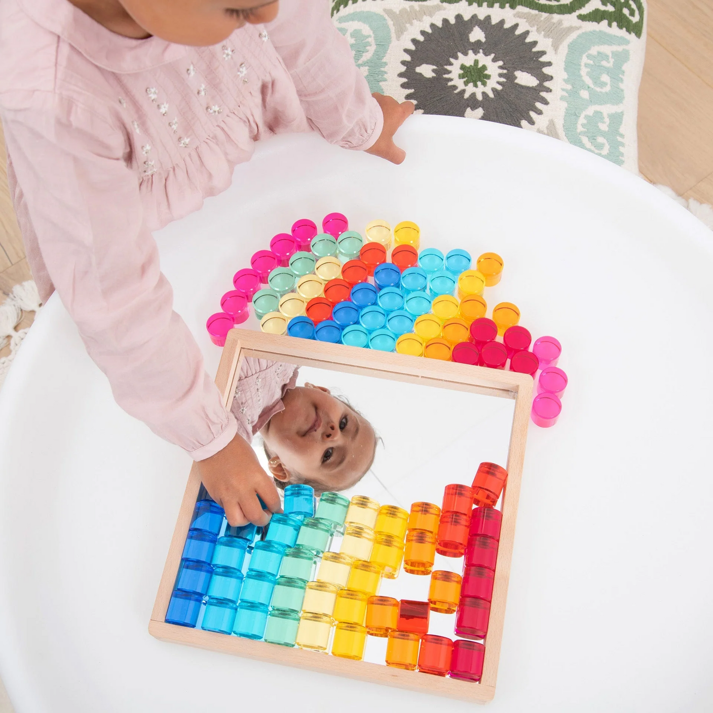 Child playing with a colourful circle sorting toy on a white surface.