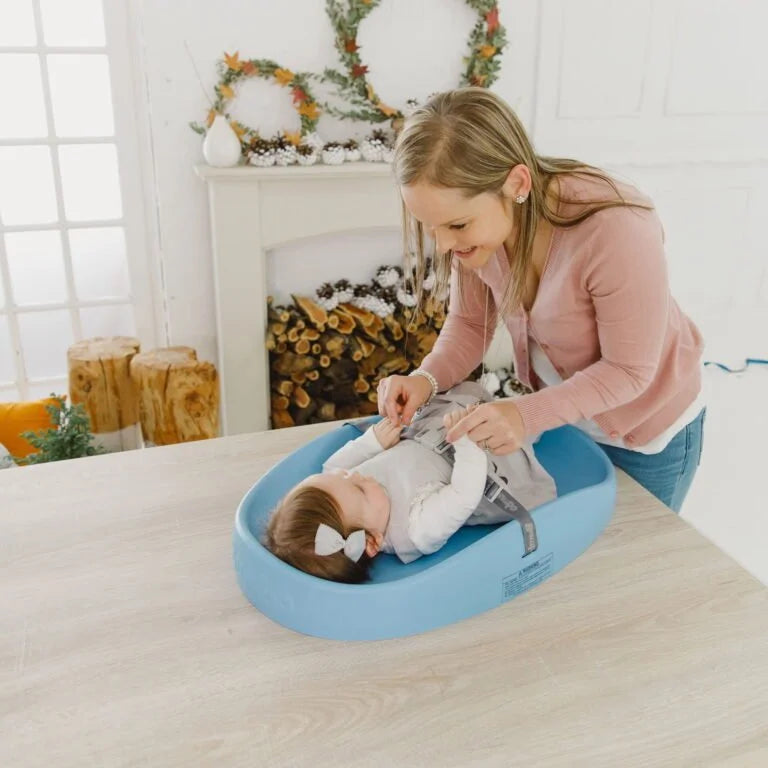 Woman adjusting a baby in a blue bassinet with festive decorations in the background