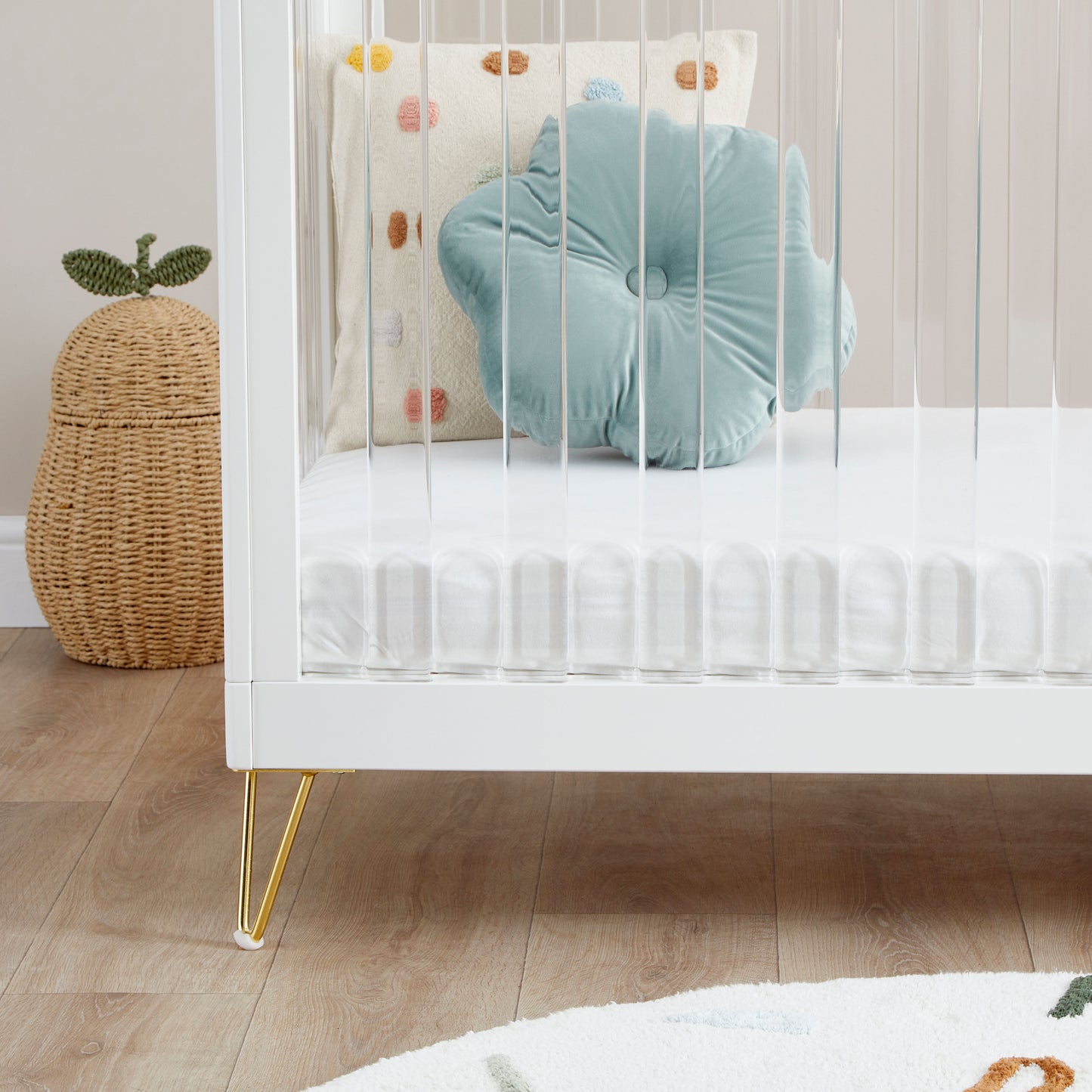 Kimi Cot Bed with a Acrylic spindles in a bedroom with rug and toys.