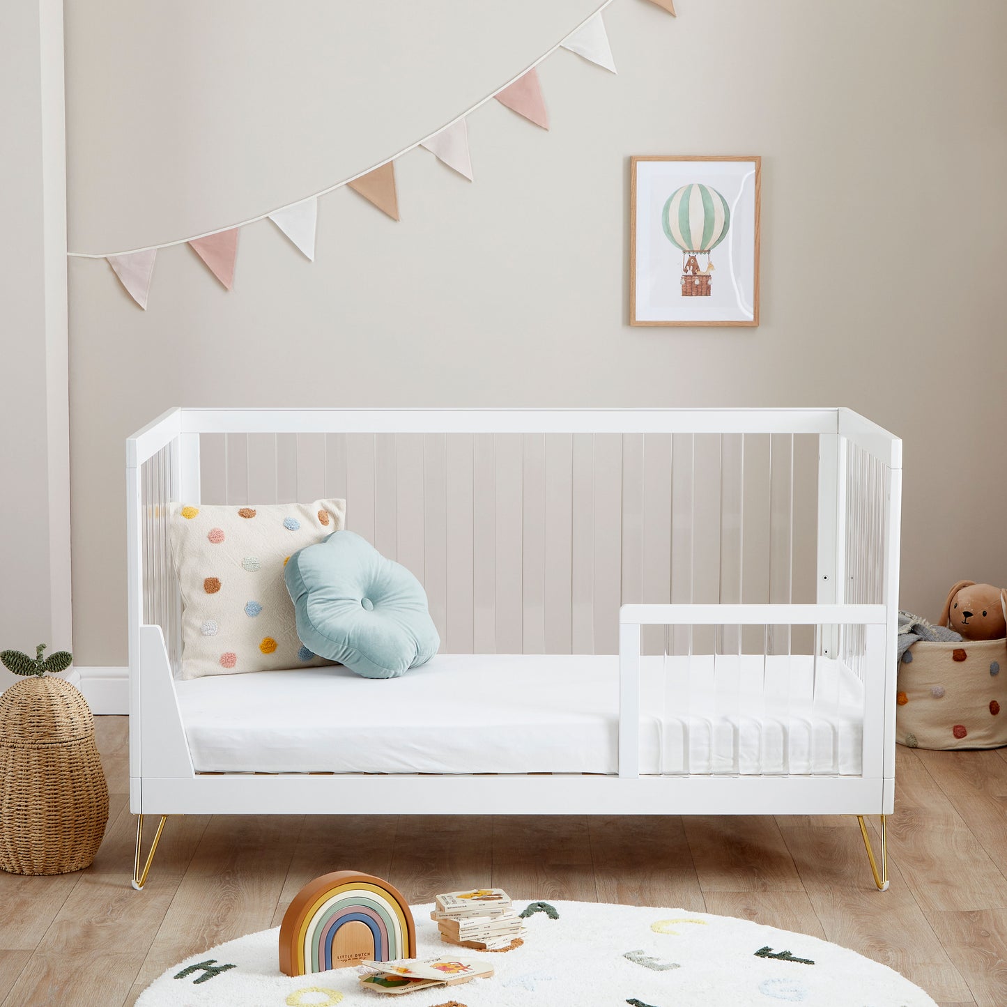 Kimi Cot Bed in toddler style with a Acrylic spindles in a bedroom with rug and toys.