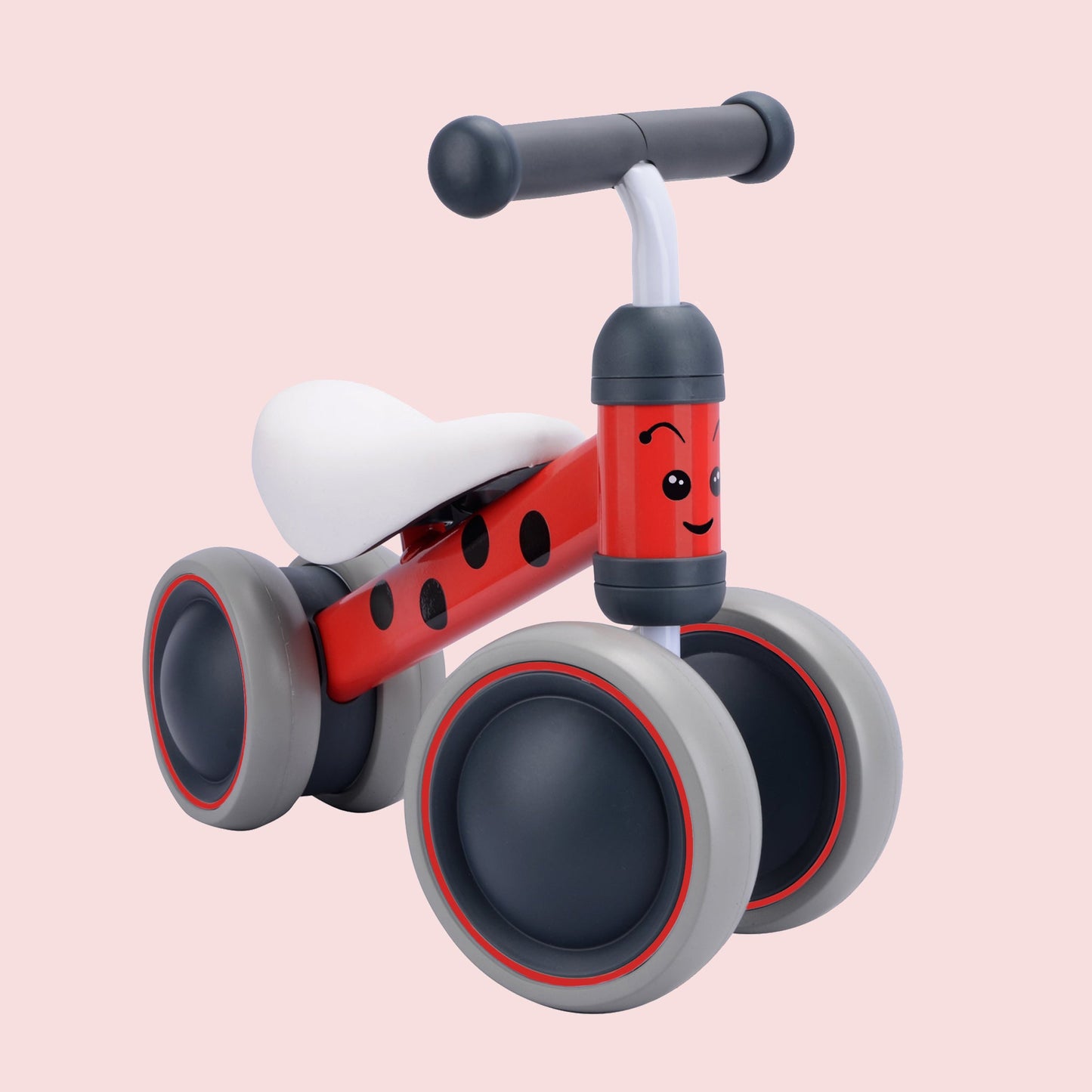 Red and gray balance bike with a smiling face on a pink background