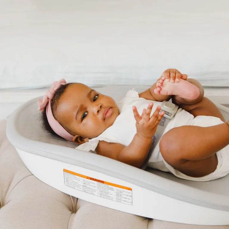 Baby lying on a white bassinet with a pink headband