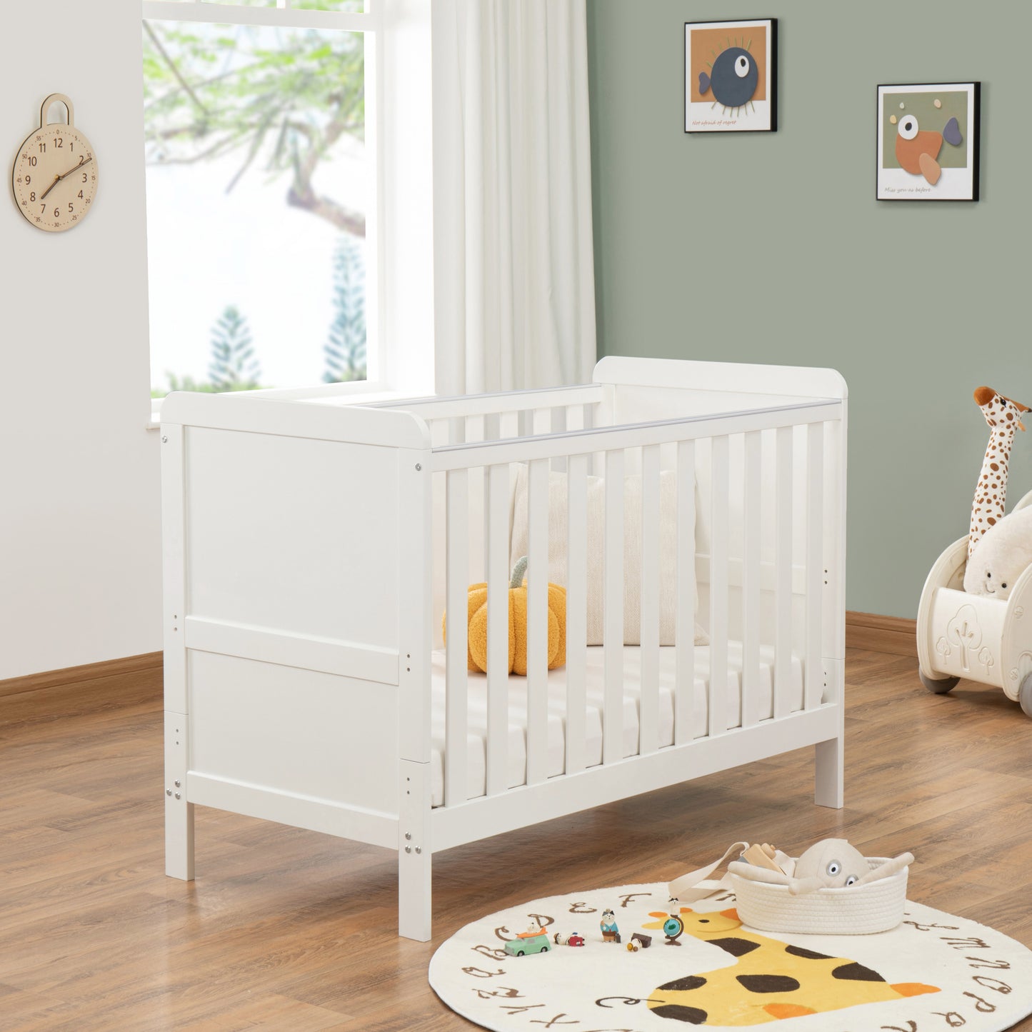 White cot in a nursery with toys and decor