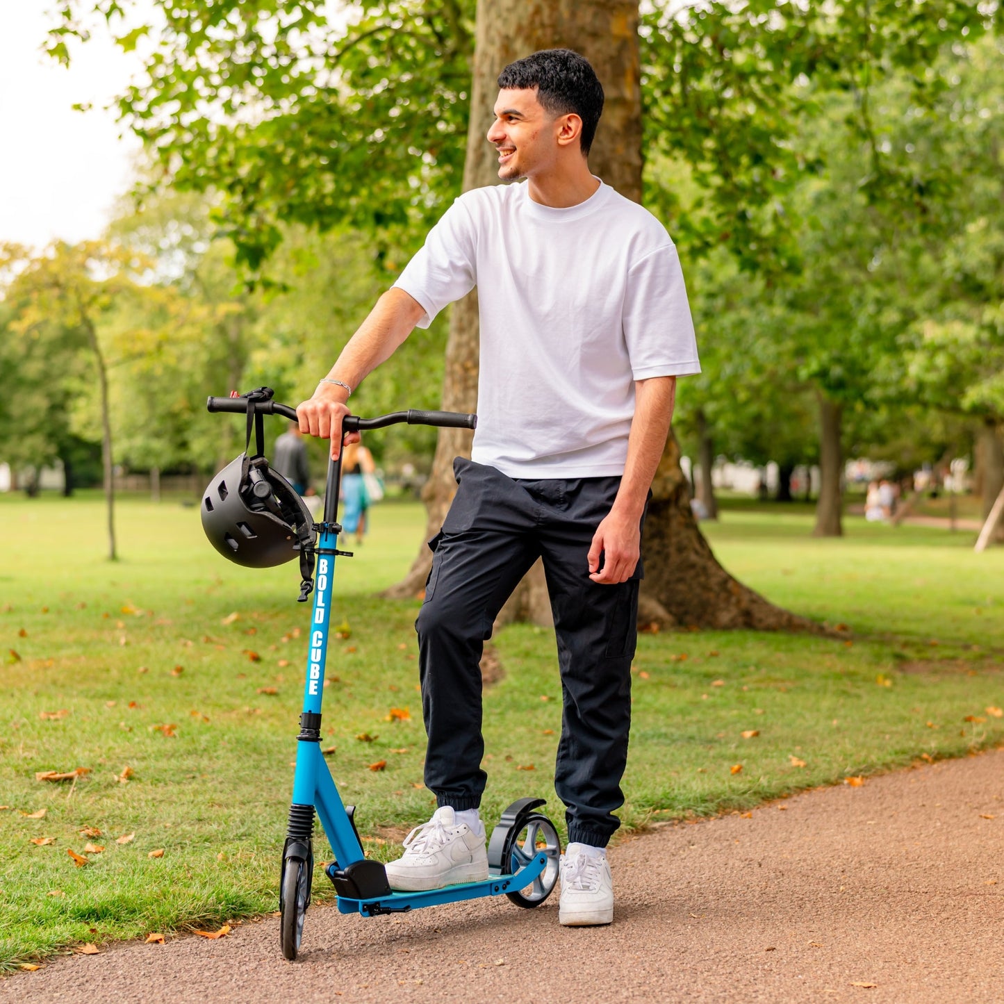 Man standing with a blue scooter in a park