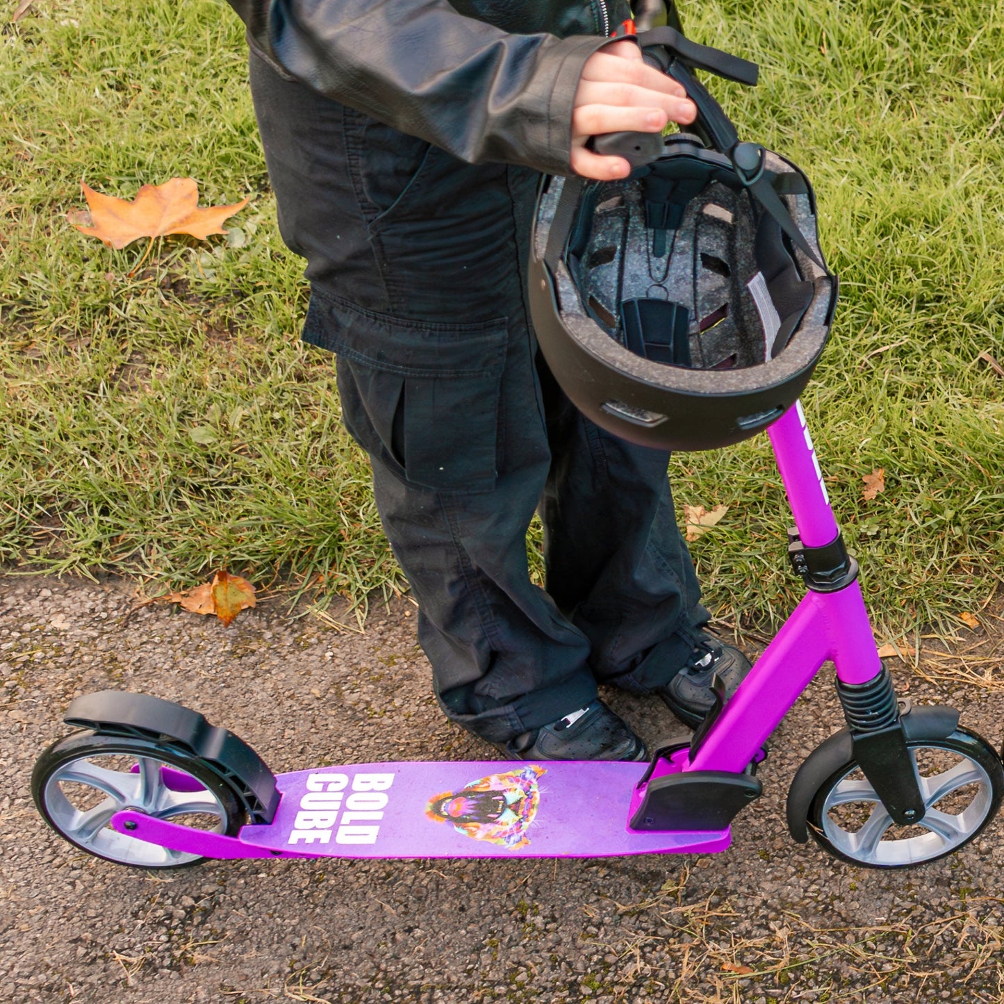 Child with a purple scooter and helmet on grass