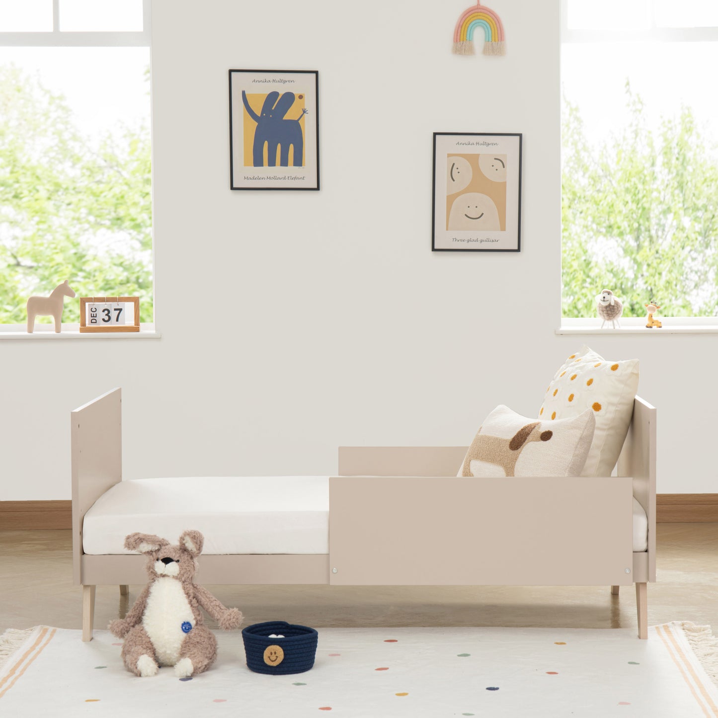 Children's room with a toddler bed, teddy bear, and toys on a light-colored rug.