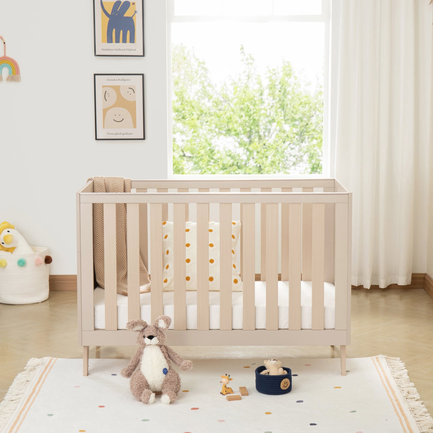 Nursery room with a crib, toys, and a window with white curtains.
