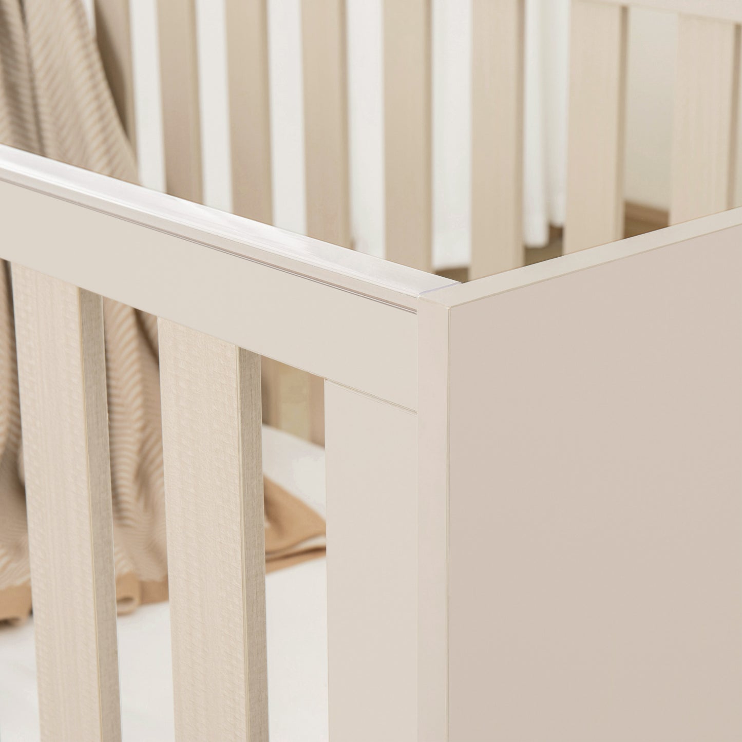 Beige cot with a soft beige blanket inside, on a light background
