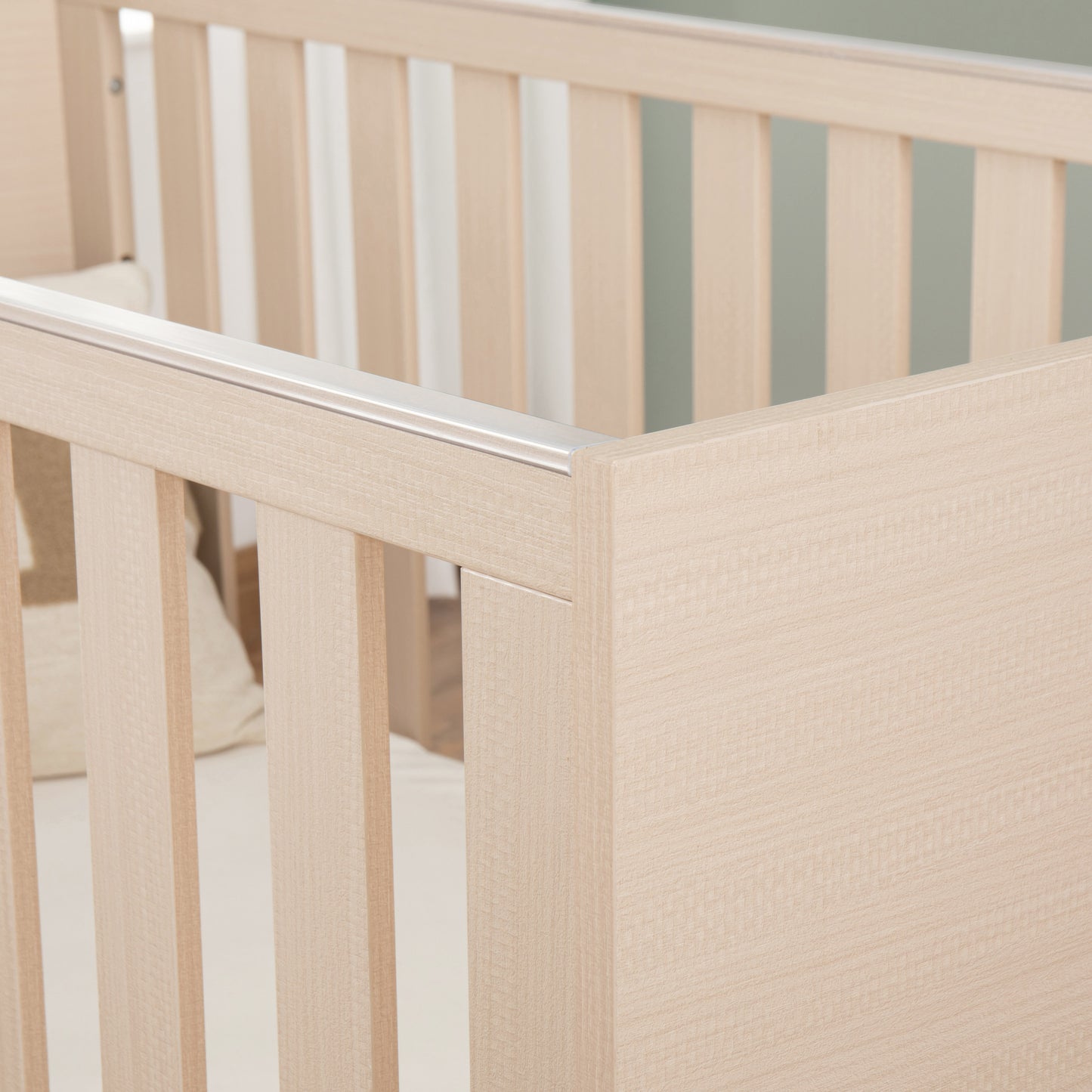 Close-up of a wooden cot with teething rail with a neutral background