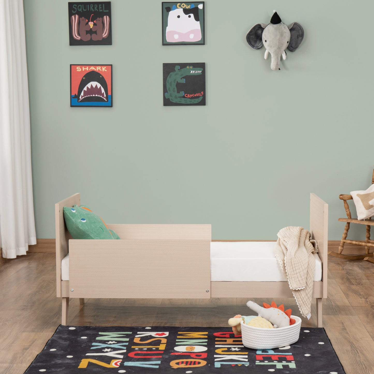 Children's room with a toddler bed, colourful posters on the wall, and a rug with letters.