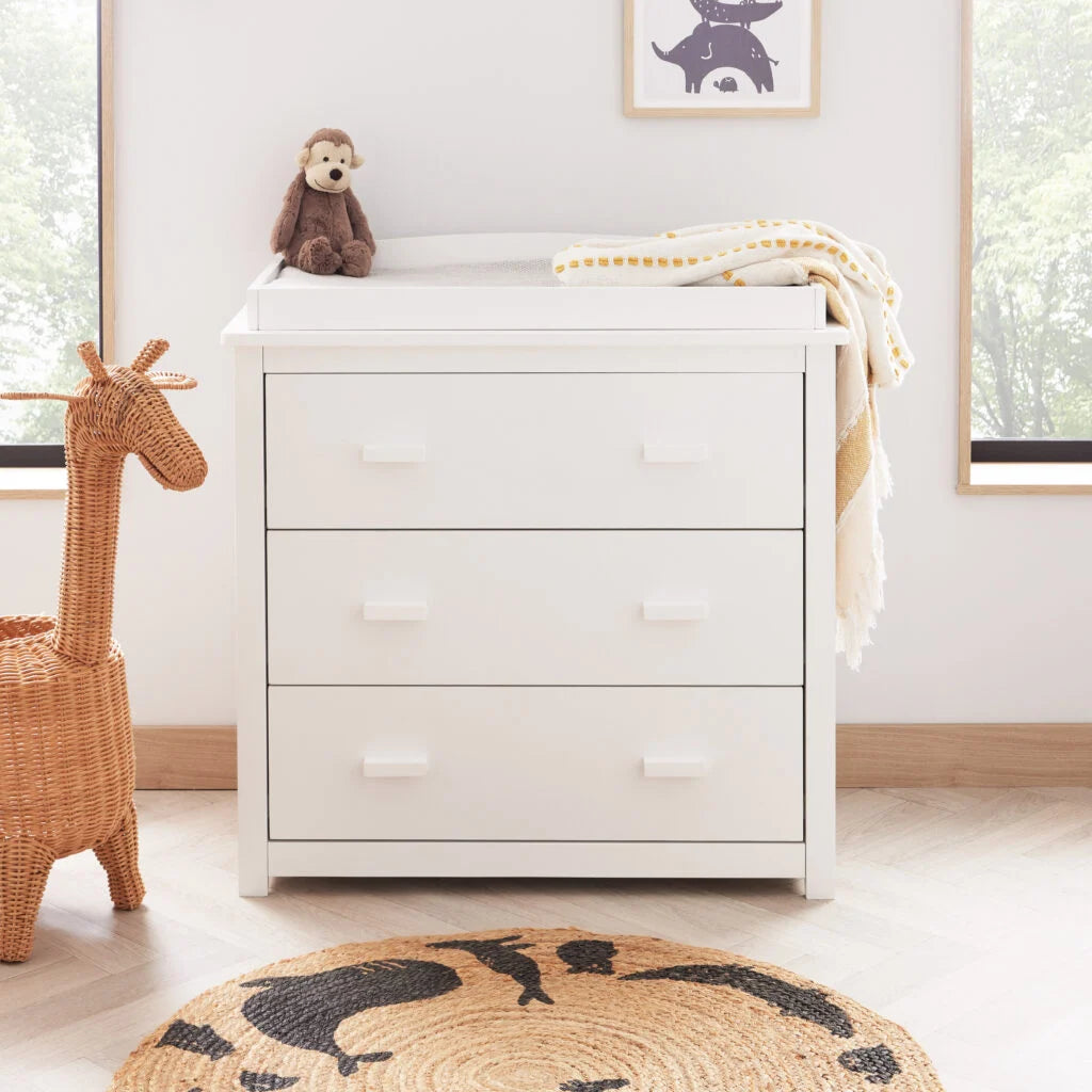 White dresser with a stuffed monkey toy in a nursery setting