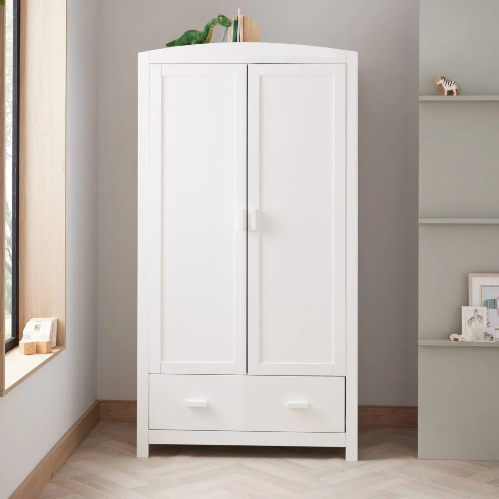 White wardrobe with a drawer in a room with a window and shelves.