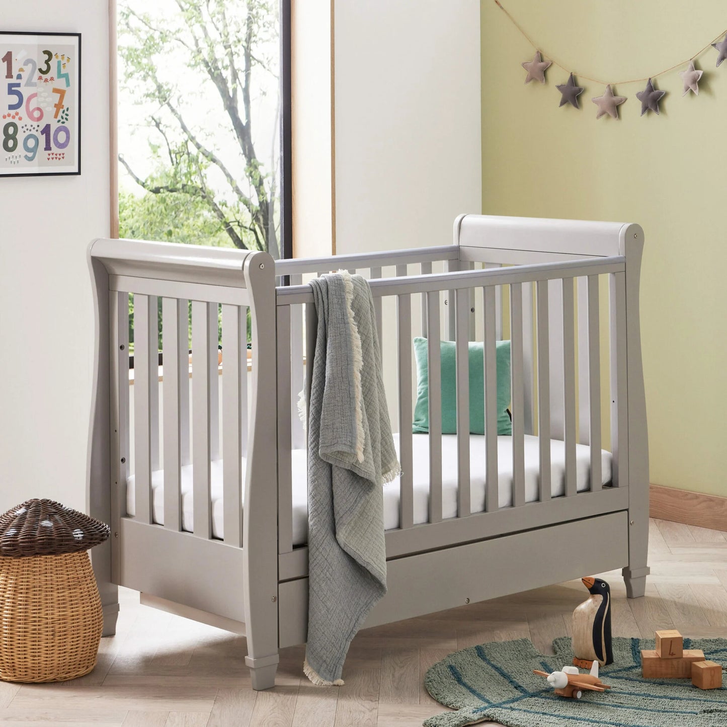 White crib in a room with toys and a window
