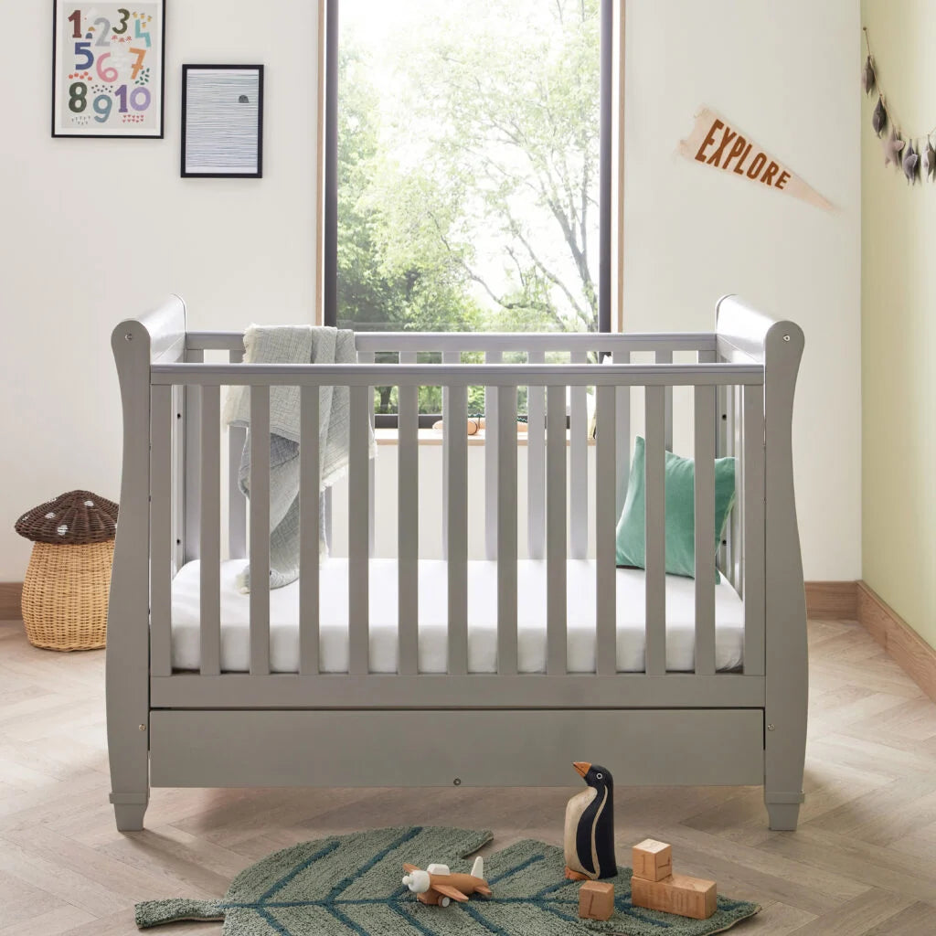Gray crib in a nursery with toys and decor