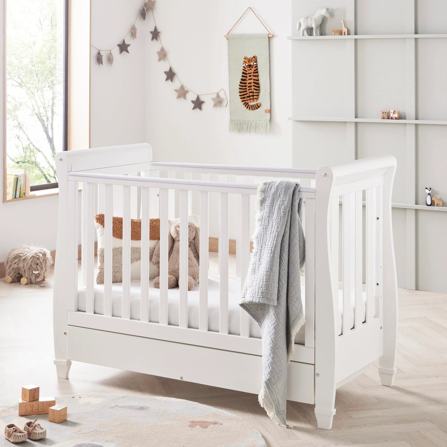 White crib in a nursery with decorative elements and toys.