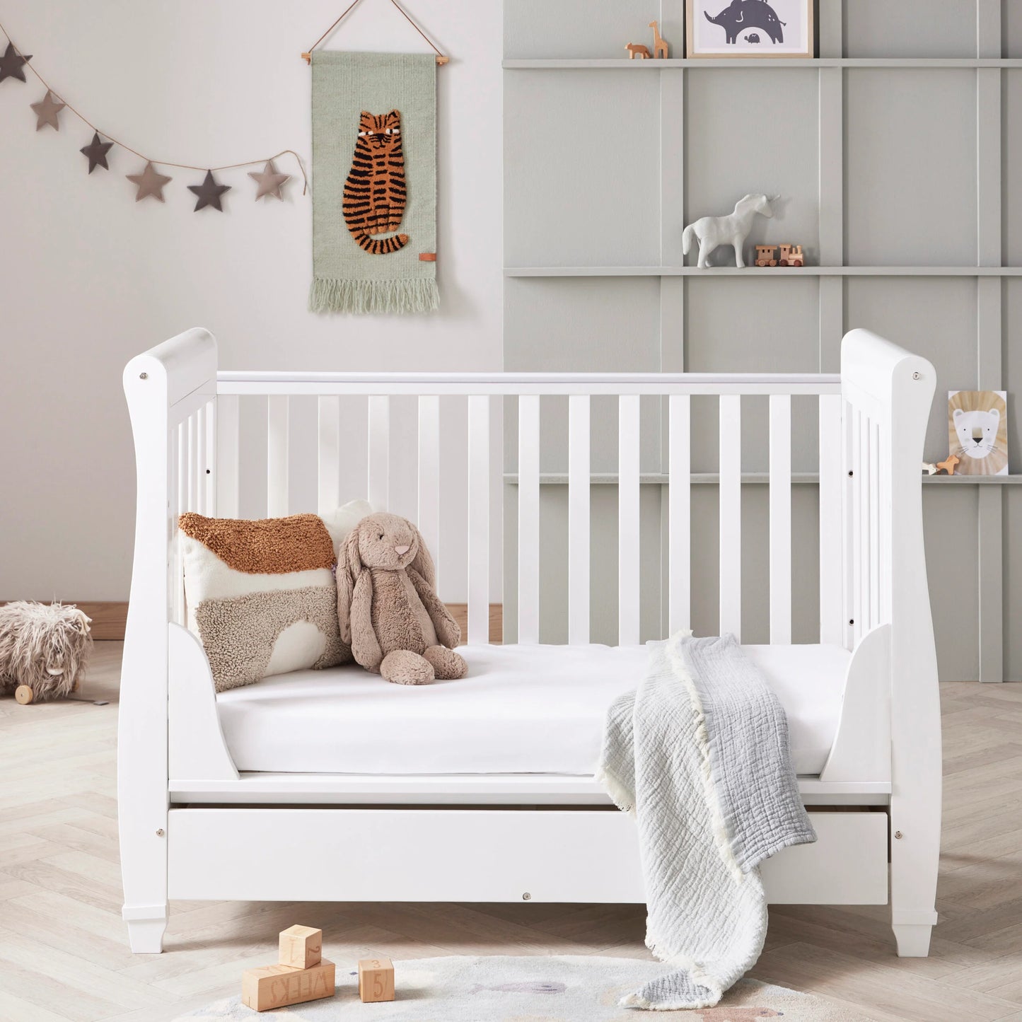White crib in a nursery with toys and decorations