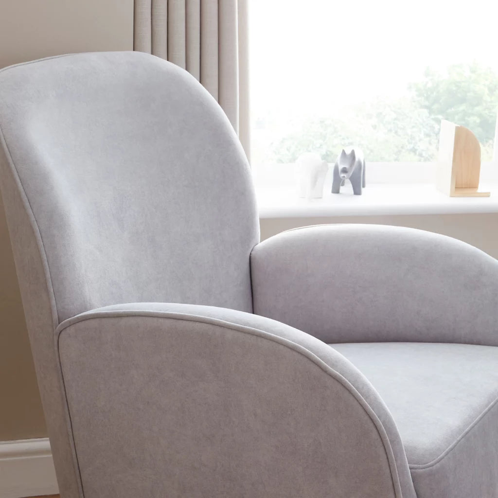 Gray armchair in a room with a window and decorative items.