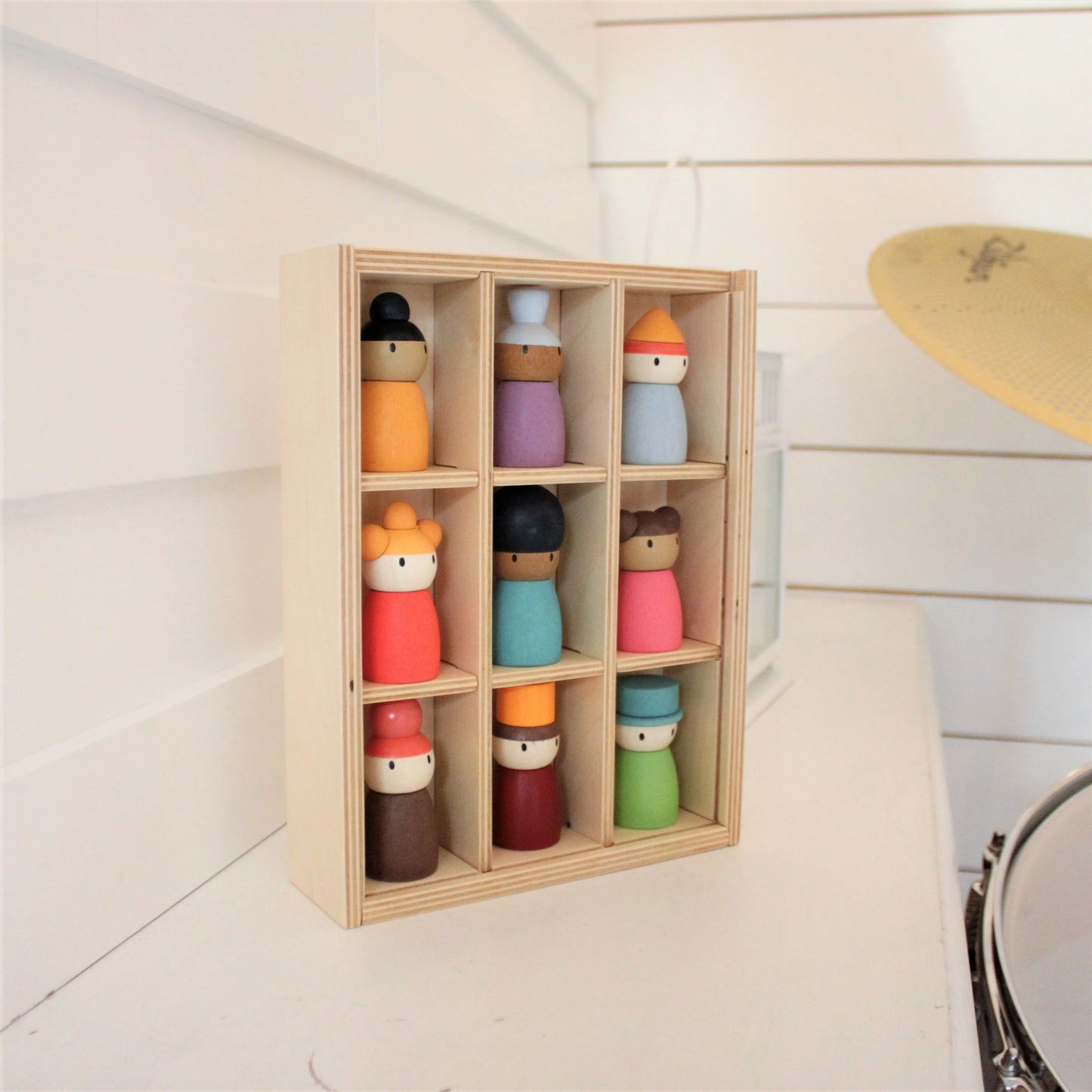 Set of colorful wooden dolls in a wooden display box on a light wooden floor.
