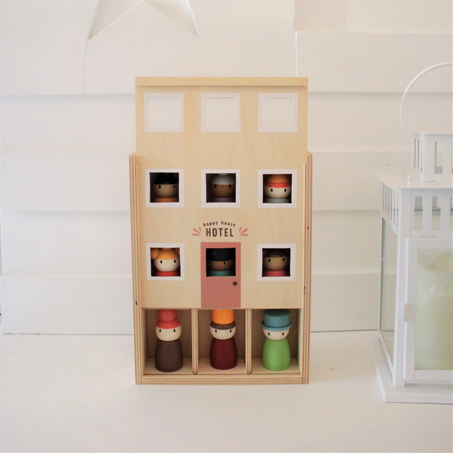Wooden toy hotel with small figurines on a white background