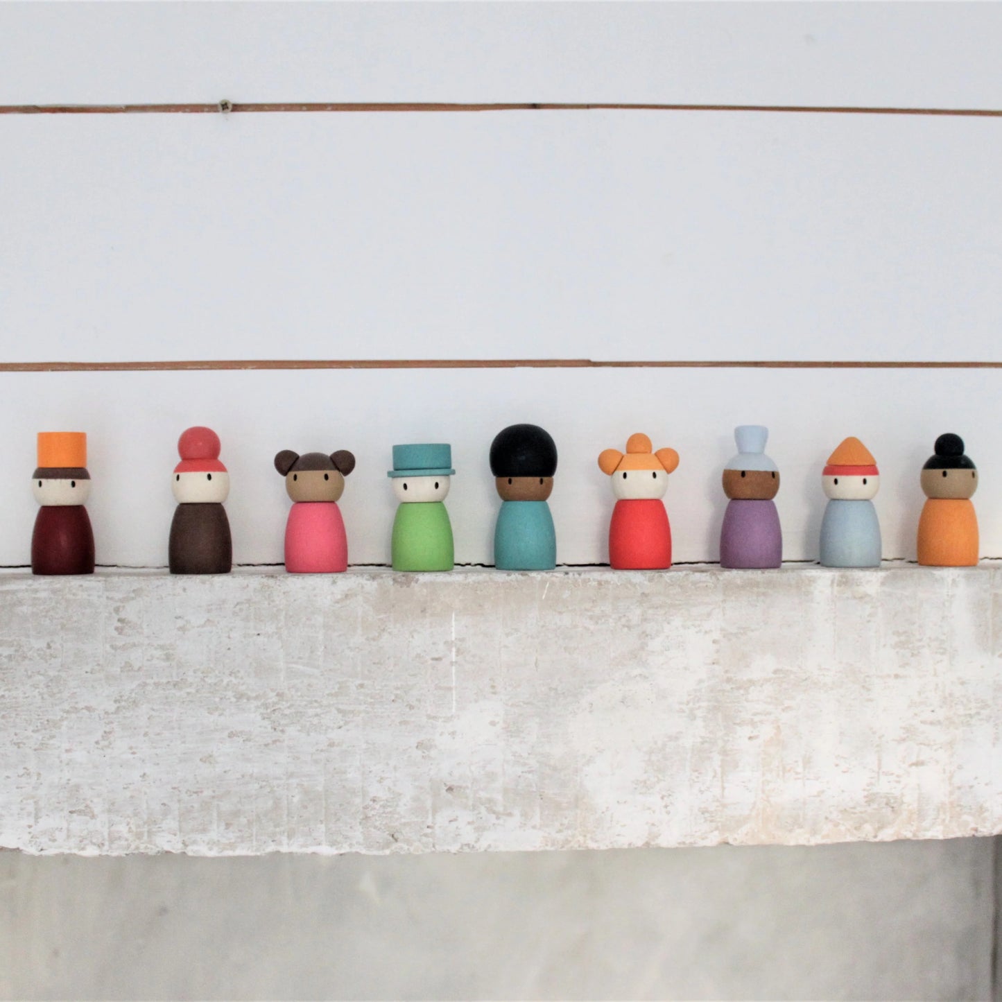 Row of colorful wooden peg dolls on a white surface with a light gray background