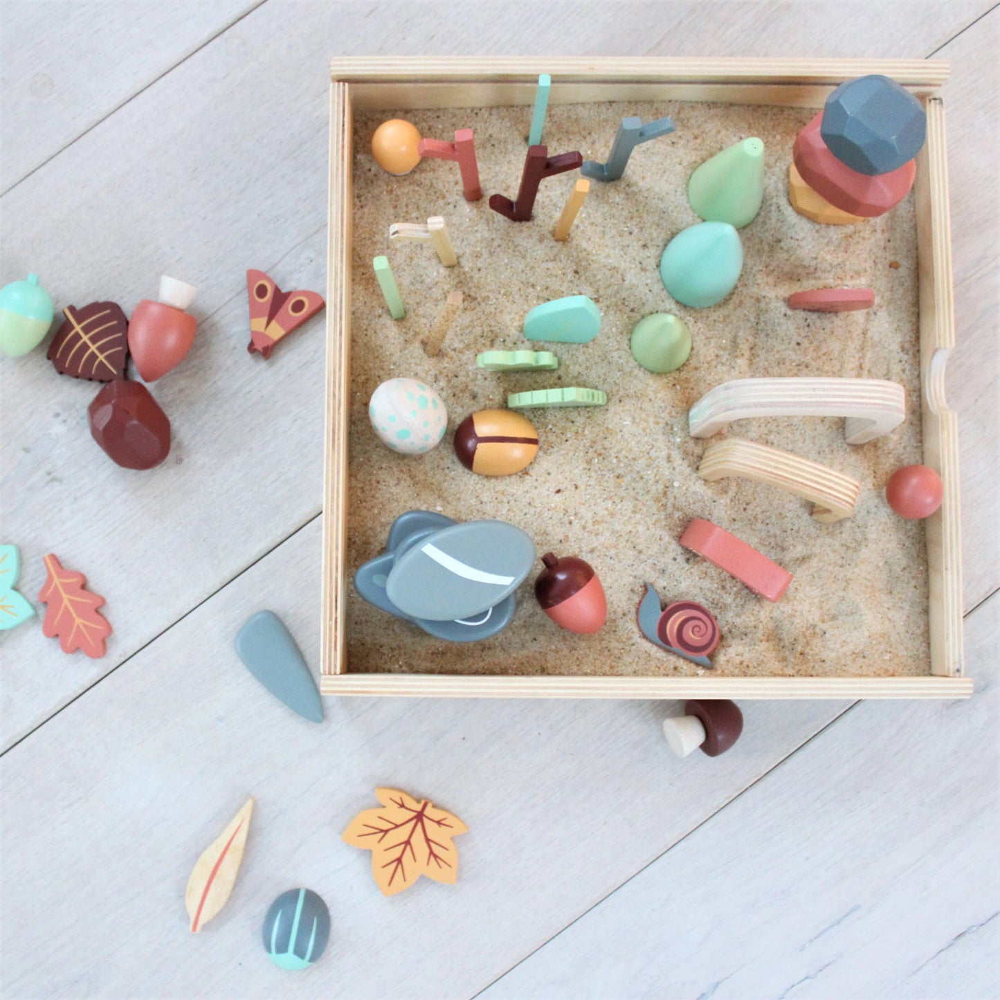 Colorful wooden toys in a box on a light gray floor
