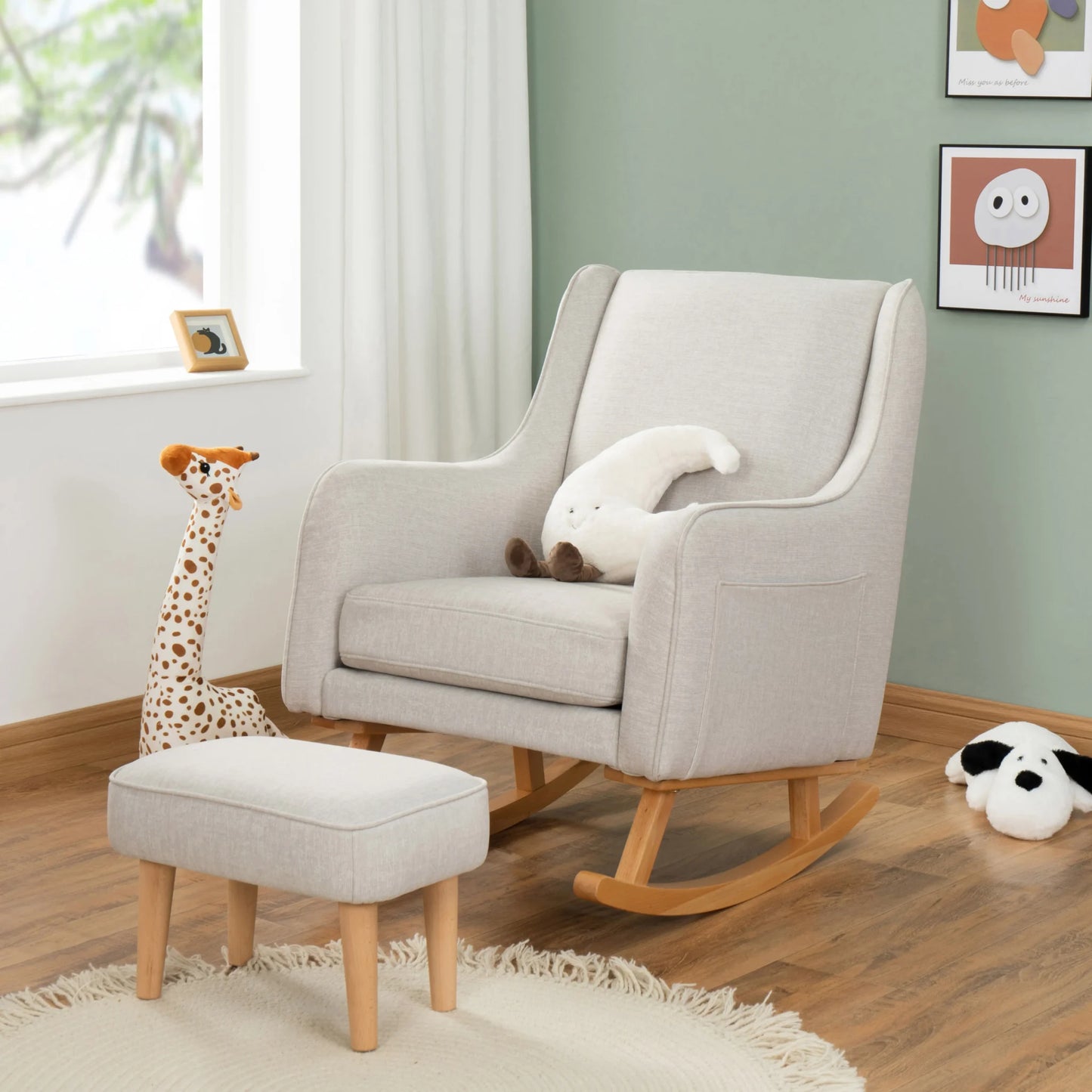 Gray rocking chair with ottoman and plush toys in a room with green walls and a window.