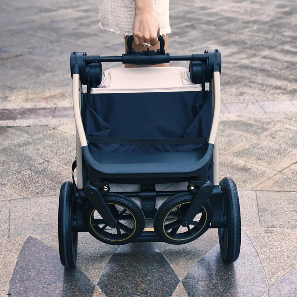 Stroller with navy cover being pushed on a paved surface