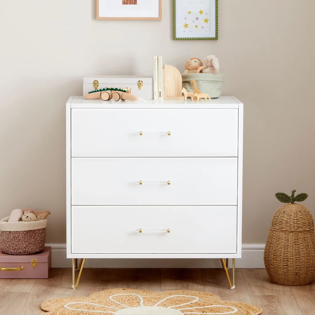 White dresser with gold legs in a child's room with toys and decor.