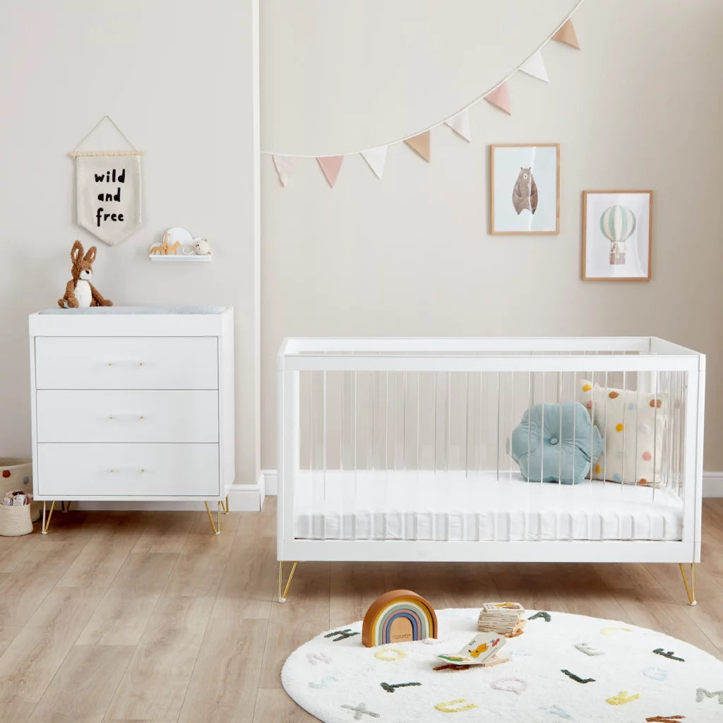 Nursery room with white crib, dresser, and decorative elements.