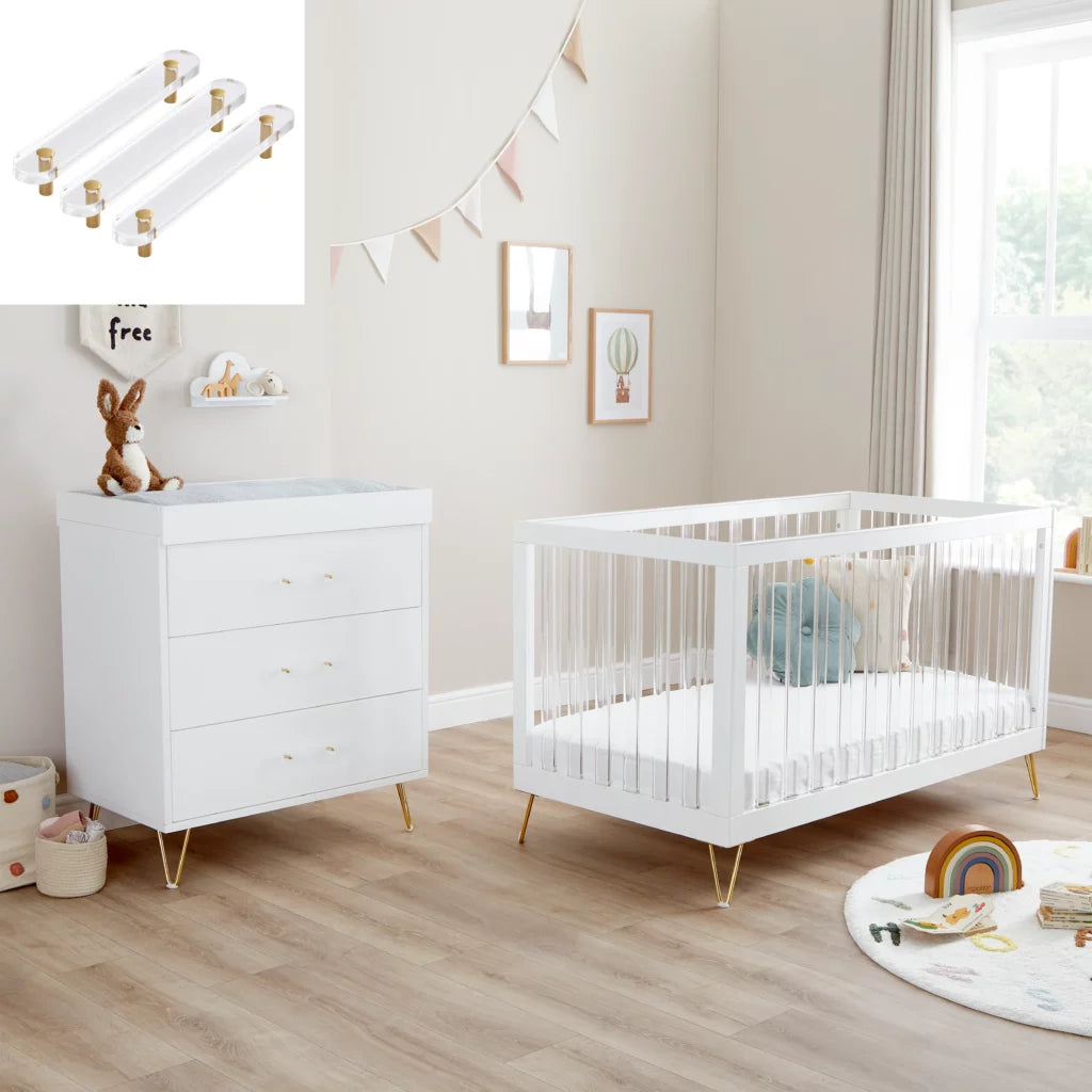 Nursery room with white crib and dresser, light wood flooring, and decorative elements.
