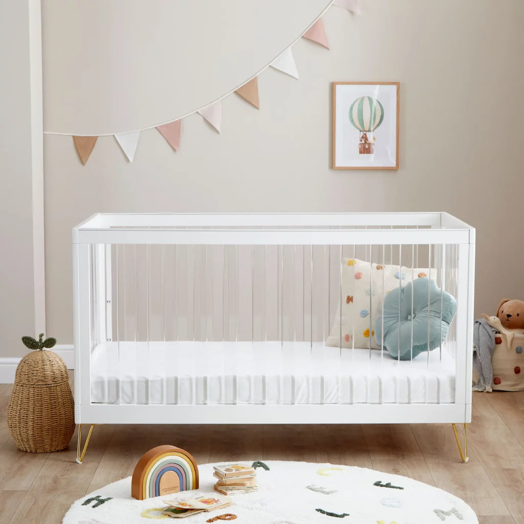 White crib in a nursery with decorative elements and toys.