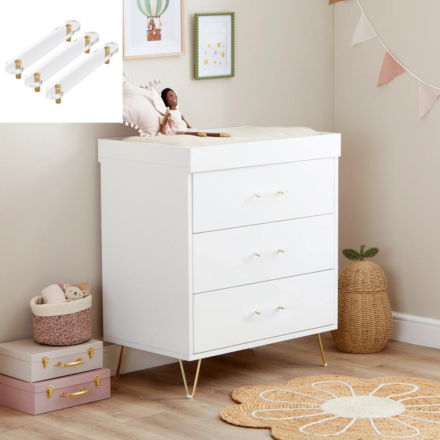 White dresser in a nursery with baby-related items and decor.