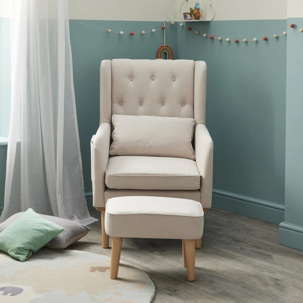 Beige armchair with ottoman in a room with teal walls and white curtains.