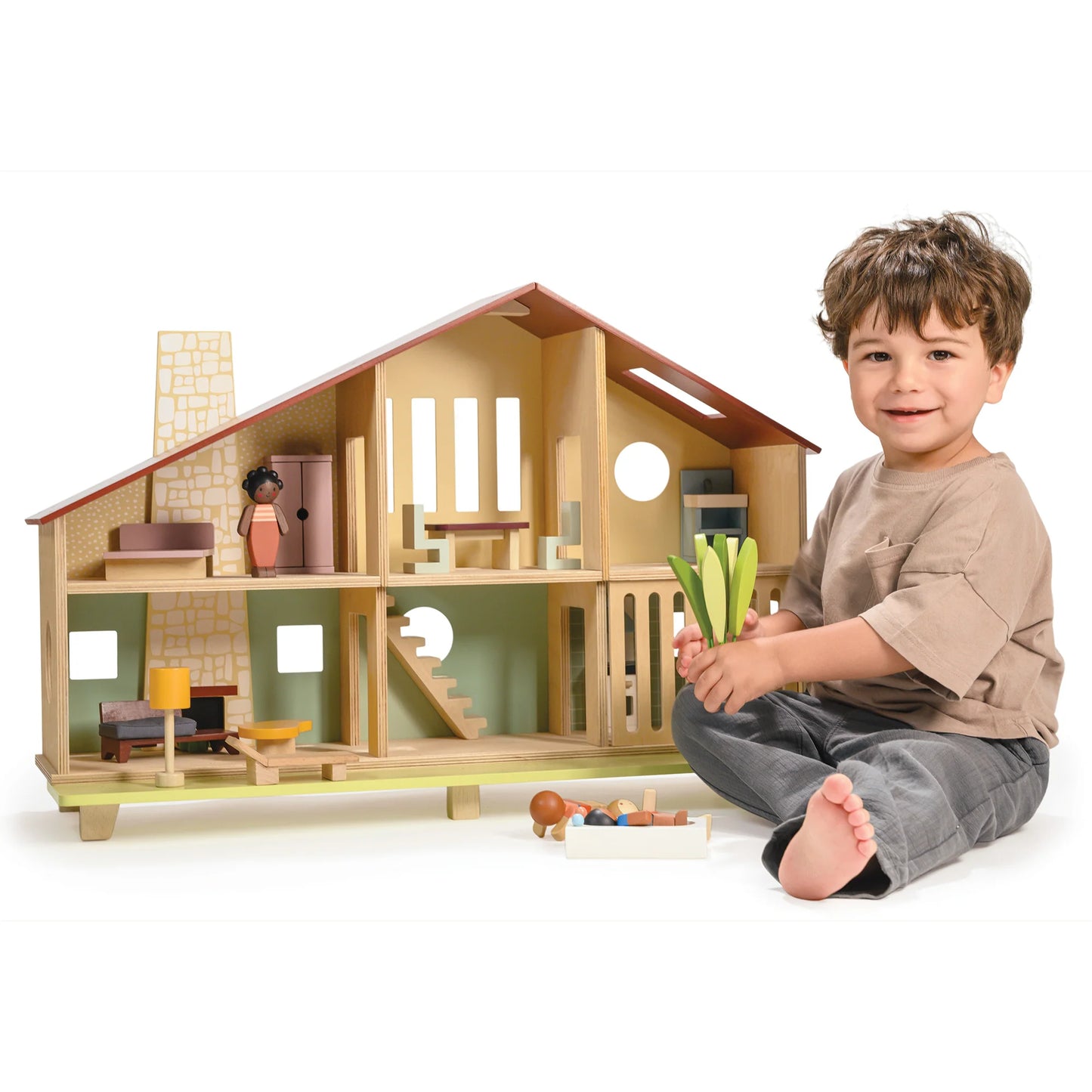 Child playing with a wooden dollhouse on a white background