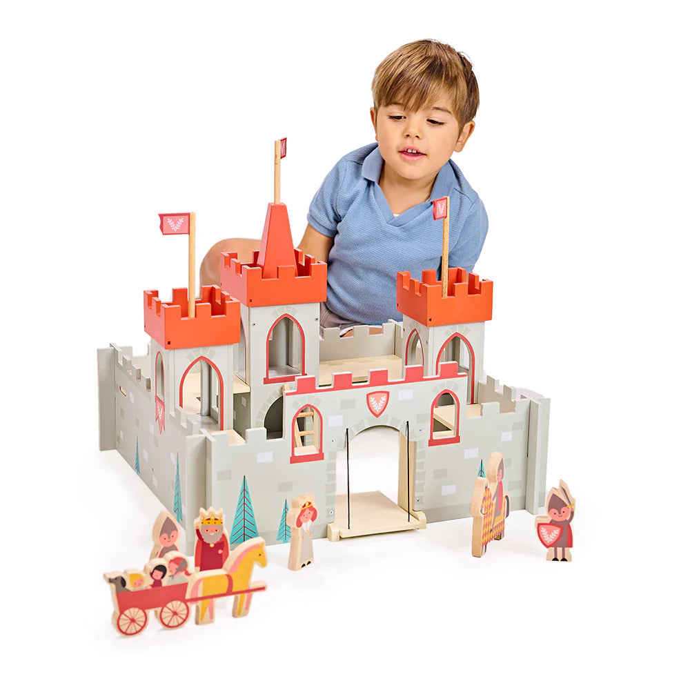 Child playing with a toy castle set on a white background
