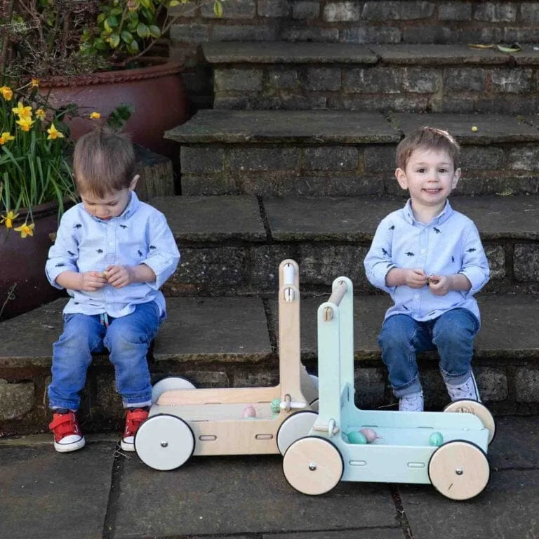 Two children playing with a wooden toy on stone steps outdoors.